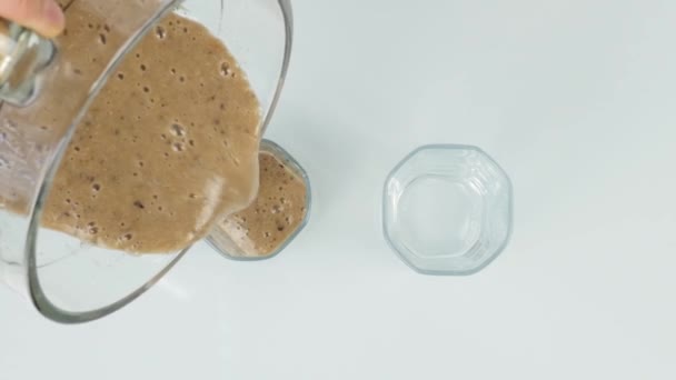 在玻璃杯中倒入水果巧克力冰沙，用于饮用健康的概念。顶部视图 — 图库视频影像