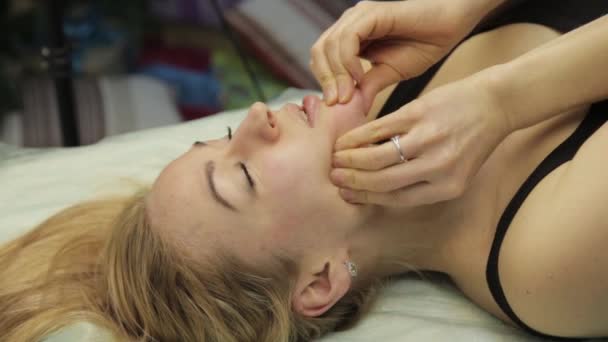 Mulher loira fazendo auto-massagem, massagem facial deitada na cama em casa — Vídeo de Stock