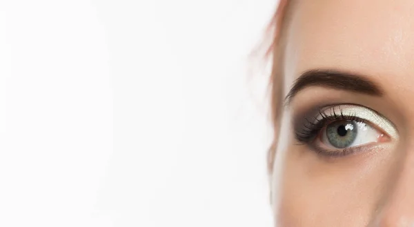 Close-up grijs oog met professionele make-up kijkend naar de zijkant, op een witte achtergrond. vrije ruimte voor tekst — Stockfoto