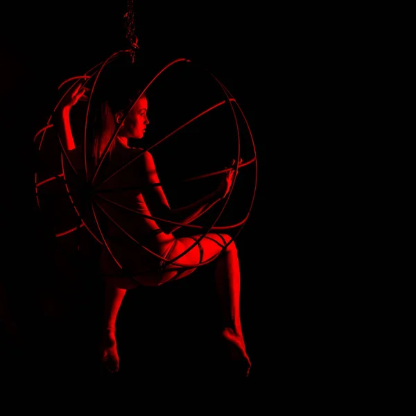 Silueta de bailarina sexy en luz roja sobre un fondo oscuro. mujer de piernas largas en un body con anillos de metal. concepto de club nocturno — Foto de Stock