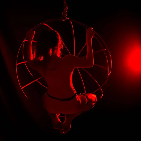 Silueta de bailarina sexy en luz roja sobre un fondo oscuro. mujer de piernas largas en un body con anillos de metal. concepto de club nocturno — Foto de Stock