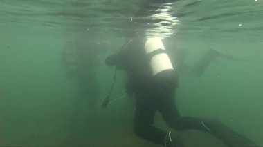 bir dağ gölü tüplü dalgıçlar keşif. yavaş çekim. kötü hava dalış, buzlu su