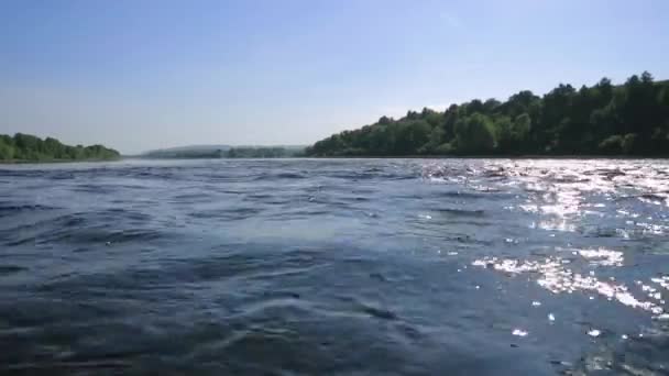 Écoulement rapide dans la large rivière peu profonde, vue sur une pierre au fond à travers l'eau. soleil éblouissement sur l'eau — Video