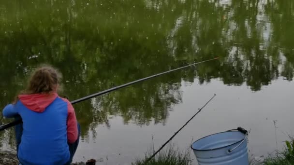 Schattig tiener meisje vissen op rivier bank staan op het zand en het houden van hengel. — Stockvideo