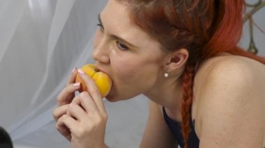 Kızıl saçlı kadın yatakta yatan süre taze meyve yiyor. sağlıklı kahvaltı. ağır çekim