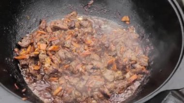 Kuzu ile pilav pişirme, havuç ve baharatlarla soğan bir ahşap üzerine bir kazan içinde soba