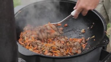Kuzu ile pilav pişirme, havuç ve baharatlarla soğan bir ahşap üzerine bir kazan içinde soba
