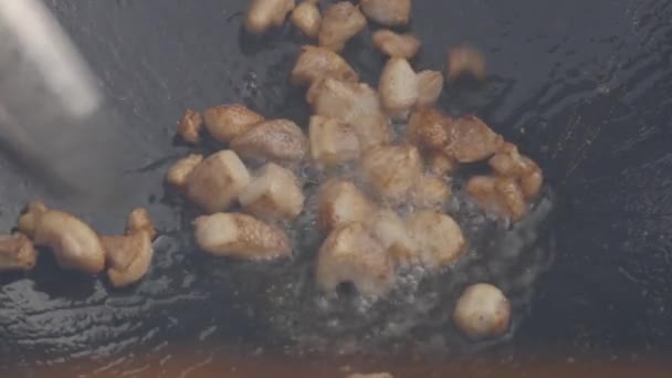 Cracklings stir fry in big frying pan. chopped meat pieces are fried in oil. slow motion — Stock Video