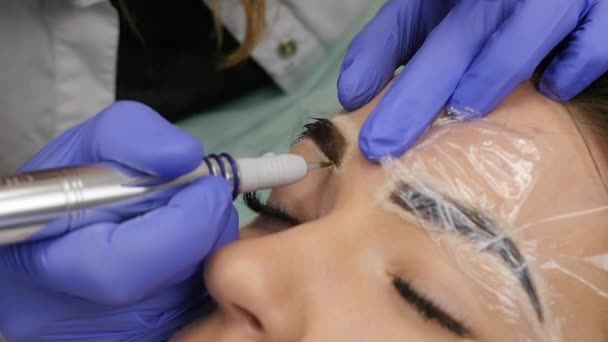 Mujer hermosa joven conseguir tatuaje de las cejas. maquillaje permanente para las cejas en el salón de belleza. cámara lenta — Vídeos de Stock