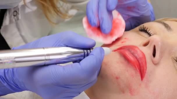 Doctor kosmetolog gör förfarandet för permanent makeup för kvinnliga klient läppar. Slow motion — Stockvideo