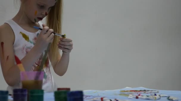 Bonito pintor menina desenha sobre a mesa e sobre si mesmo em suas roupas. câmara lenta — Vídeo de Stock