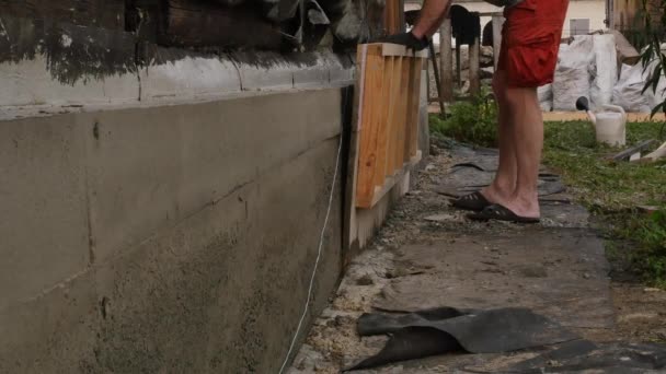 Werknemer ontmantelt de houten bekisting, nieuwe Stichting voor oud huis. 4k — Stockvideo