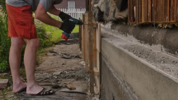 Trabalhador desmonta a cofragem de madeira, nova fundação para a casa velha. 4K — Vídeo de Stock