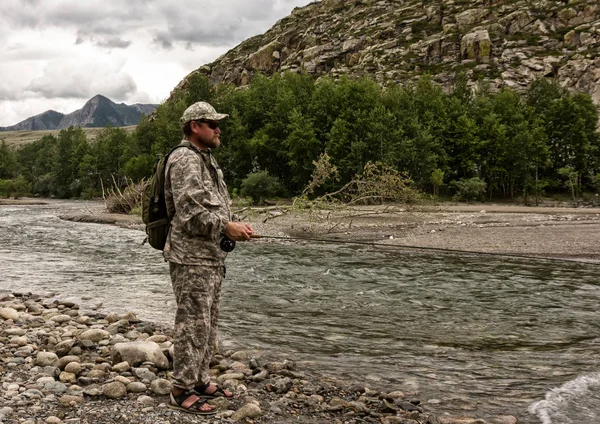 Singolo pescatore su un fiume tempestoso sta pescando in una giornata estiva soleggiata — Foto Stock