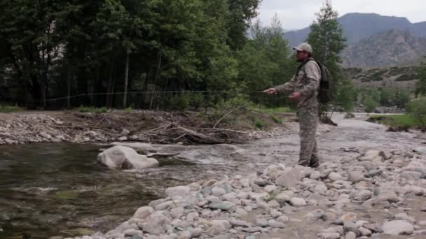 Singolo pescatore su un fiume tempestoso sta pescando in una giornata estiva soleggiata — Video Stock