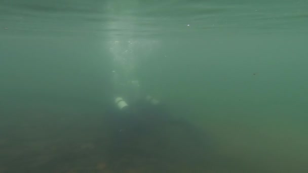 Buceadores exploran el fondo rocoso en aguas poco profundas. entrenamiento de buceadores jóvenes. cámara lenta. sumergirse en un lago de montaña — Vídeos de Stock