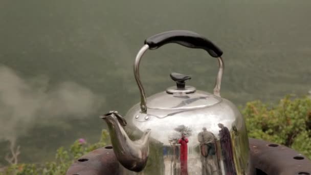 The iron kettle is boiling on the shore of a mountain lake. camping concepte — Stock Video
