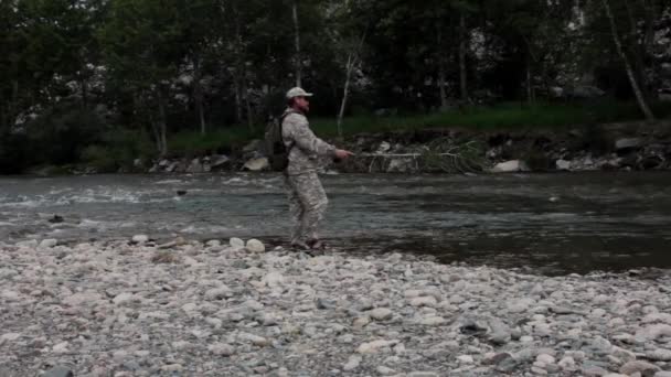 Одинокий рыбак на бурной реке рыбачит в солнечный летний день — стоковое видео