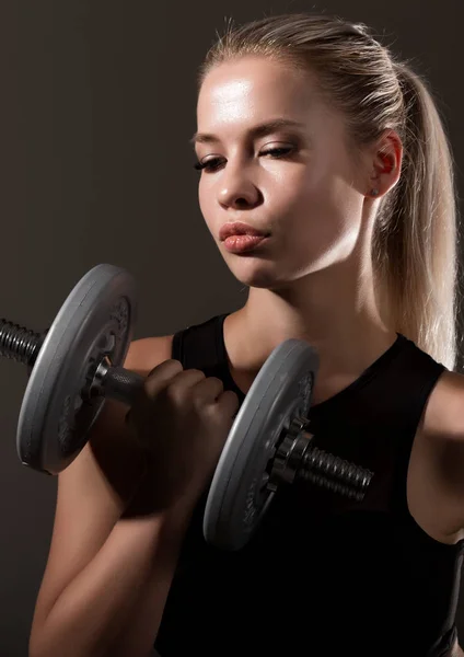 Σέξι κοπέλα γυμναστικής με αλτήρες σε σκούρο φόντο. Αθλητής που κάνει ασκήσεις στο γυμναστήριο — Φωτογραφία Αρχείου