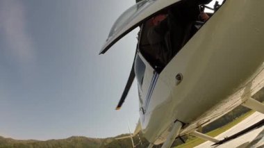 Helikopter kalkışa hazırlanıyor, pilot kapıyı kapatıyor. Küçük hafif havacılık. Bir pervanenin alt görünümü