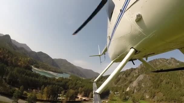 Lågflygande helikopter flyger över flodbädden i ett bergigt område. Liten lättviktare. bottenvy på propellerblad — Stockvideo