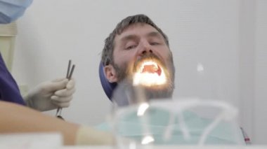 Kadın dişçi, diş kliniğinde bir hastayı tedavi ediyor. Diş muayenesi. Stomatolog hastaların dişlerini tedavi eder.