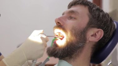 Kadın dişçi, diş kliniğinde bir hastayı tedavi ediyor. Diş muayenesi. Stomatolog hastaların dişlerini tedavi eder.