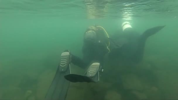 Dykare utforska den klippiga botten i grunt vatten. unga dykare utbildning. Slow motion. ner i en fjällsjö — Stockvideo