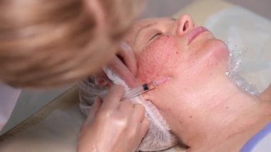 Güzellik doktoru klinikte kadın yüzü için yaşlanma önleyici iğne yapıyor. Güzellik salonunda biyo-evrimleşme prosedürü. cilt bakımı ve yüz gerdirme kavramı