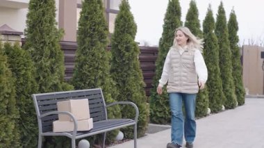 Yeşilliklerle dolu bir yolda yürürken kadın bir paket teslim eder.