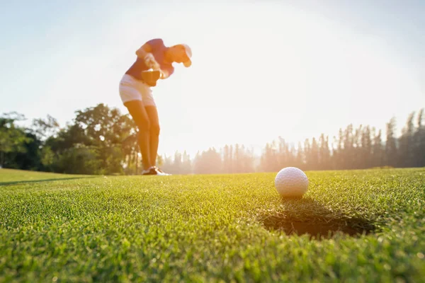 Golfçü Asyalı kadın odak tarih Pzr yeşil golf Golf topu koyarak akşam saat ayarla... Sağlıklı yaşam konsepti