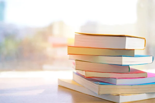 Kütüphanedeki kütüphane odasında kitap yığını ve kütüphanenin penceresinin yanındaki güneşli bir günde eğitim. Eğitim Konsepti