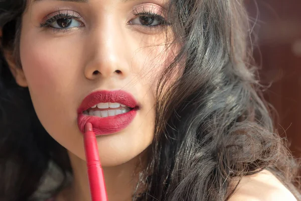 Beautiful luxury young woman applying lip liner to nude red lips. Close up shot and make up cosmetic of woman putting lipstick on her lip
