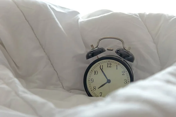 ビンテージの目覚まし時計は 晴れた日の朝に白いベッド シート 布団や枕に起きる ライフ スタイルのコンセプト — ストック写真