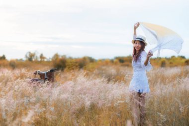 Yaşam tarzı kadın beyaz elbise vintage Bisiklet ile sakin ve mutlu yaz aylarında çayır sonbahar çiçek bulutlu gün batımı veya gündoğumu gökyüzünde, arka plan alanını kopya alanı yazıt için. Yaşam tarzı ve tatil kavramı