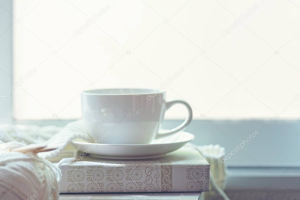 offee Cozy winter home with warm knitted sweaters and ball of yarn  near windowsill, cup of hot coffee marshmallow, home hobbies.  Lifestyle Concept