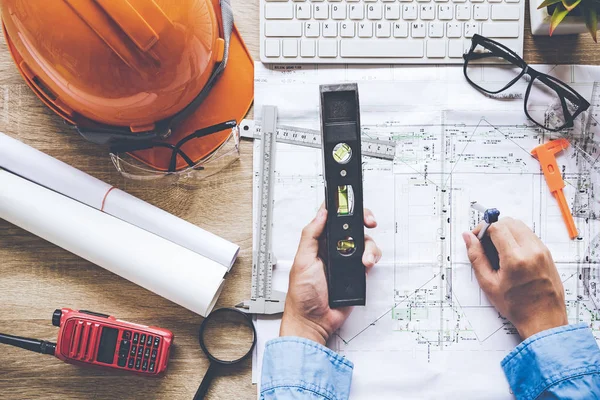 Top View Architect working on blueprint. Architects workplace.  Engineer tools and safety control,  blueprints, ruler, orange helmet,radio,laptop and divider compass. Construction Concept.