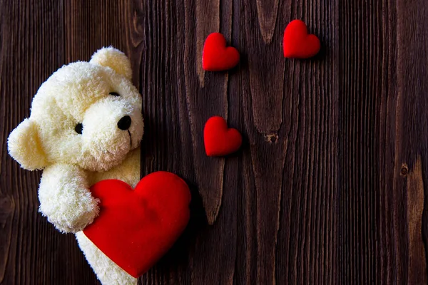 Cute teddy bear with red heart on old wood, copy space.  Valentine Concep