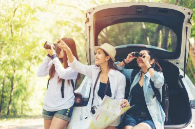 Grup Asyalı kadın gezgin hatchback araba gezisi road ile açık havada orman için tatil ve tatil gezileri oturan seyahat. Seyahat kavramı