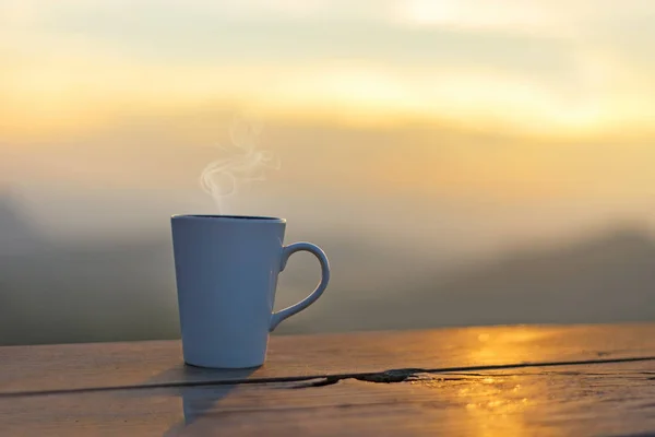 Cup coffee and tea with steam on wood table outdoor over mountains landscape with sunlight. Beauty nature background. Lifestyle Concept