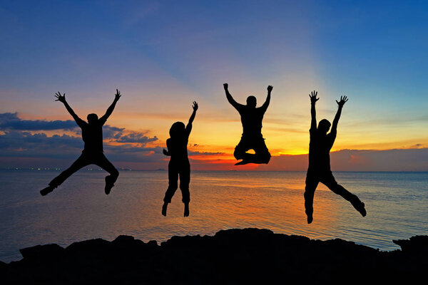 Silhouette of friends and teamwork jumping on beach during sunset time for success business. Lifestyle and Teamwork Concept