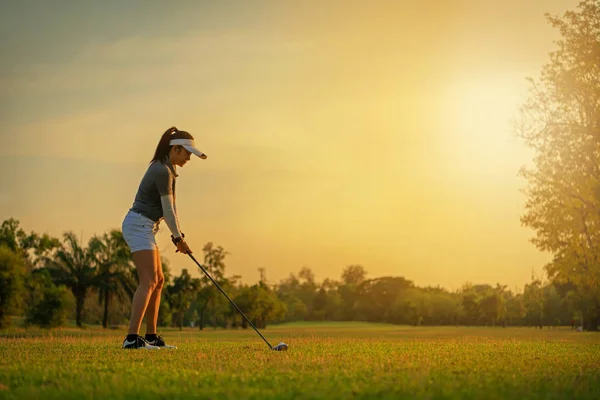 Spor sağlıklı. Asyalı sportif kadın golf oyuncu golf salıncak tee yapıyor kapalı yeşil günbatımı akşam zamanında o muhtemelen egzersiz. Sağlıklı yaşam konsepti
