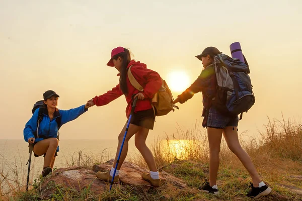 团体徒步队女子帮助她的朋友爬上山中最后一段日落 游客团队合作和家人放松步行在户外生活方式的冒险和露营 旅游暑期生活理念 — 图库照片