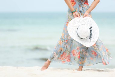 Yaz tatili. Büyük beyaz şapka tutarak el kapatın. Lifestyle kadın kumlu okyanus plajında ayakta moda yaz gezileri giyiyor. Mutlu kadın zevk ve tatil dinlenmek. Yaşam tarzı ve seyahat cONCEP