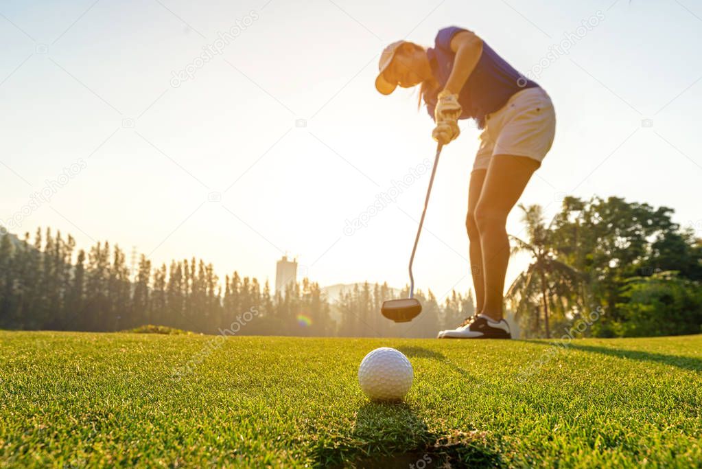 Sport Healthy. Golfer asian sporty woman focus putting golf ball on the green golf on sun set evening time.  Healthy and Lifestyle Concept 