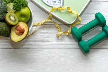 Diyet ve Sağlıklı yaşam kaybı kilo Kavramı. Yeşil elma ve Ağırlık ölçeği ölçmek kadınlar diyet zayıflama için taze sebze ve spor ekipmanları ile dokunun. Üst görünüm ve kopyalama aralığı