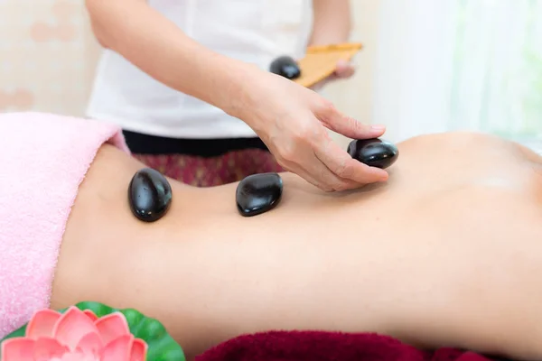Asia beauty woman lying down on massage bed with traditional balinese hot stones along the spine at Thai spa and wellness center, so relax and lifestyle. Healthy Concep