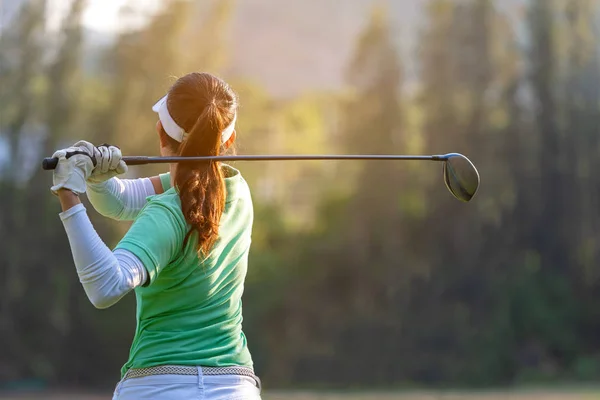 Spor sağlıklı. Asyalı sportif kadın golf oyuncu golf salıncak tee yapıyor kapalı yeşil günbatımı akşam zamanında o muhtemelen egzersiz. Sağlıklı yaşam konsepti.