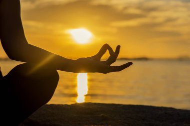 Siluet ellerini kapat. Kadın dışarıda yoga yapıyor. Sunset Beach arka planında spor yapmak ve spor yapmak için meditasyon yapan bir kadın. Sağlıklı Konsept