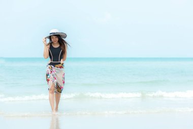 Yaz tatili. Yaşam tarzı kadın soğuk büyük beyaz şapka tutarak ve bikini moda yaz gezileri kumlu okyanus plajda yürüyüş giyiyor. Mutlu kadın keyfini çıkarın ve tatil dinlenmek. Yaşam Tarzı ve Seyahat Konsepti